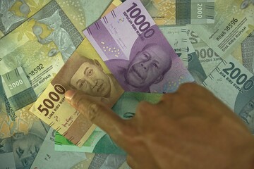 5000, 10000, 20000 IDR, Indonesian Rupiah money concept was held by businessman on money background