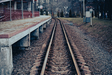 Obraz premium Railway station. An empty platform and railway rails in cloudy weather. High quality photo
