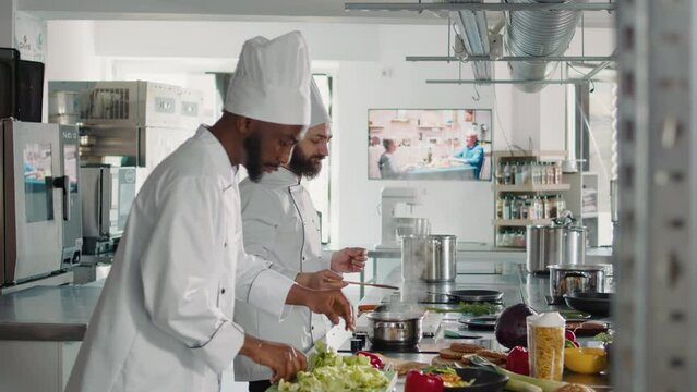 Male cook doing taste test with delicious sauce on stove, testing soup to make gourmet meal in kitchen. Professional chef using culinary recipe with ingredients for gastronomy restaurant service.