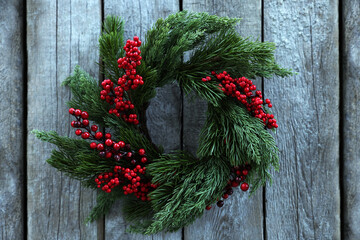 Beautiful Christmas wreath with red berries hanging on wooden wall