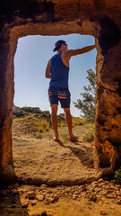 A young man wandering around Kato Paphos Archeological Park. He is standing in front of an entrance...