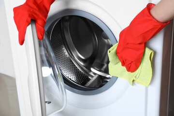 Woman cleaning washing machine with rag, closeup