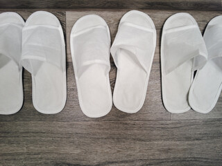 Top view photo of spa white slippers on wooden background