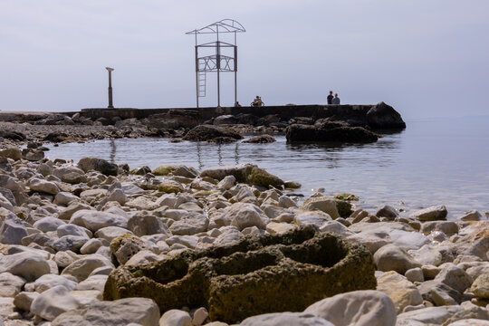 Scenic shot of a rocky beach and people resting and ooking at the sea