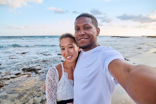 Happy couple in love taking selfie together on smartphone, on beach