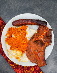  Flat lay of Traditional South African Braai or Shisa nyama, meat cooked on an open flame and traditional side dish of pap and chakalaka.