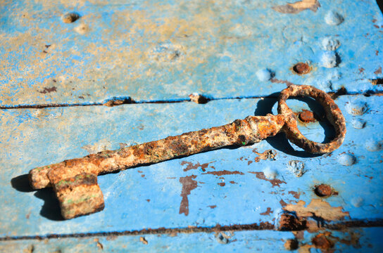 Old rusty key on a grungy blue wooden surface