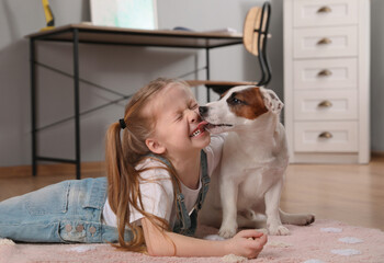 Cute little girl playing with her dog at home. Childhood pet - obrazy, fototapety, plakaty