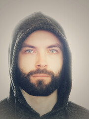 Portrait of a young man with a beard. A man in a hood.