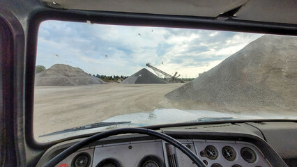 Point of view shot from the driver's side of an old truck at a query driving to pick up gravel - obrazy, fototapety, plakaty