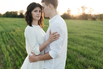  Portrait of a young romantic couple hugging each other in a field at sunset