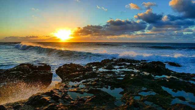 Rocky Shore Of The Ocean With Yellow Sunset And Cloudy Sky On The Background