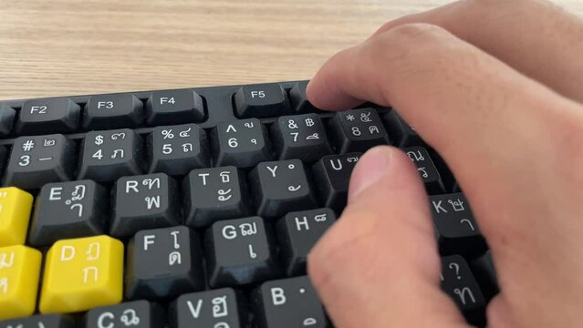 Typing on keyboard. Male hand fingers pressing F5 button key on English - Thai computer black keyboard close up shot. Work from home professional hand press F5 to reload and refresh the page browser