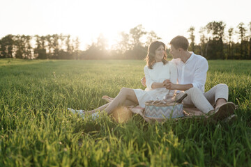 The lovely beautiful couple in love sitting on green grass. Romantic love story in the park. Young girl and boy in love.