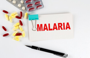 MALARIA text written in a card with pills. Medical concept.