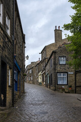 Fototapeta na wymiar The steep and cobbled Main Street in the village of Haworth, West Yorkshire, UK: empty of people on a wet afternoon