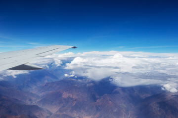 Fototapeta na wymiar Aerial view of cloud blue sky and plane wing view through the airplane window.