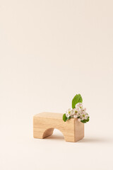 Light beige wooden product display podium with flowers on beige background. Minimal empty mockup counter showcase product presentation scene with copy space. Wooden cubes, front view
