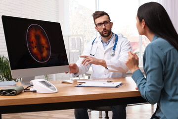 Neurologist showing brain scan to young woman in clinic