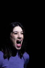 angry brunette woman screaming on a black background