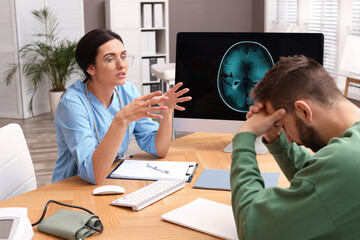 Neurologist consulting patient at table in clinic - obrazy, fototapety, plakaty