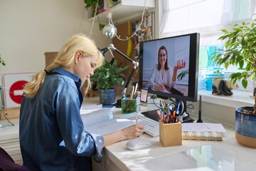 Teenage girl studying at home online using computer