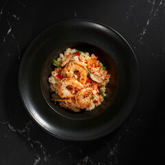 Fried rice with shrimp and vegetables on a dark stone background.