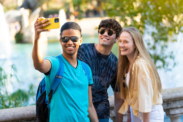 Obraz premium Group of young friends taking a selfie on vacation visiting a landmark.
