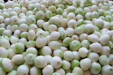 A scattering of peeled onions on a supermarket shelf. Sale of fresh vegetables in the market.