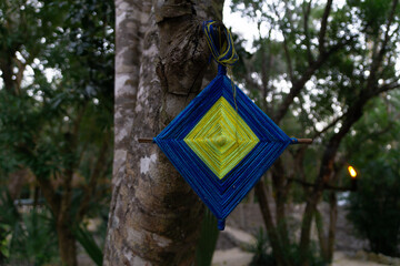 Traditional Mayan amulet made of threads. Amulet of the Mayan tribe on a tree at dusk. Maya Mexican...