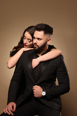 Handsome bearded man with sexy lady on light brown background