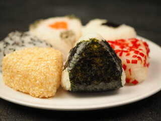 Onigiri of various shapes and fillings on a plate. Close-up food photo. Japanese rice ball.