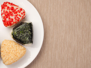 A series of shots of onigiri of various shapes and fillings on a plate. Top view. Japanese rice ball.
