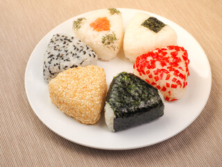 A series of shots of onigiri of various shapes and fillings on a plate. Top view. Japanese rice ball.