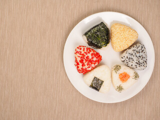 A series of shots of onigiri of various shapes and fillings on a plate. Top view. Japanese rice ball.