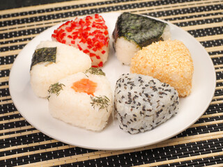 A series of shots of onigiri of various shapes and fillings on a plate. Top view. Japanese rice ball.