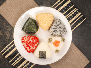 A series of shots of onigiri of various shapes and fillings on a plate. Top view. Japanese rice ball.