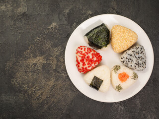A series of shots of onigiri of various shapes and fillings on a plate. Top view. Japanese rice ball.