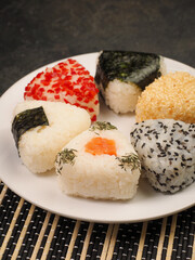 A series of shots of onigiri of various shapes and fillings on a plate. Top view. Japanese rice ball.
