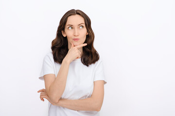 Fototapeta premium portrait of brunette caucasian woman with thoughtful face, looking away in white T-shirt on white background