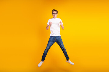 Fototapeta na wymiar Full body photo of young cheerful man rejoice victory fists hands jump isolated over yellow color background