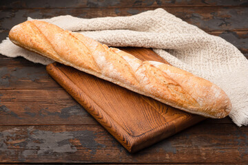 Bread, baguette, boton, rye on a wooden background.