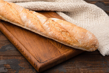 Bread, baguette, boton, rye on a wooden background.