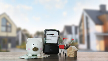 Electricity meter, house model, piggy bank and shopping cart with money on wooden table against...