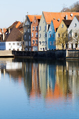 Fototapeta premium Colorful beautiful city houses on the coast illuminated by the sun. Cityscape Landsberg Am Lech reflected in the river. River Lech, Romantic Road Bavaria Germany