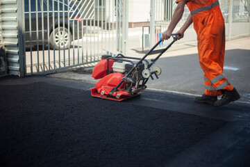 Asphalt laying. Leveling the road. A worker compresses warm asphalt.