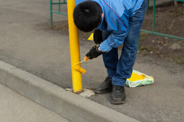 Painting a metal post with yellow paint. Parking bollard painting.