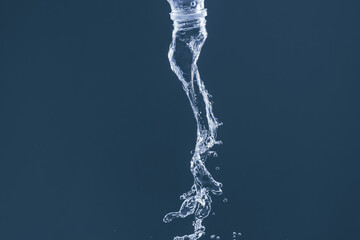 Fototapeta na wymiar Splash of water from a bottle on a blue background. Reflection on the surface of the water.