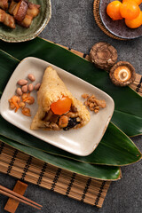 Zongzi, rice dumpling for Dragon Boat Festival on dark gray table background with ingredient.