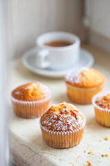 Sweet muffins with powdered sugar and blossoms. Homemade bakery. Muffins in white capsules decorated with fruit tree flowers.